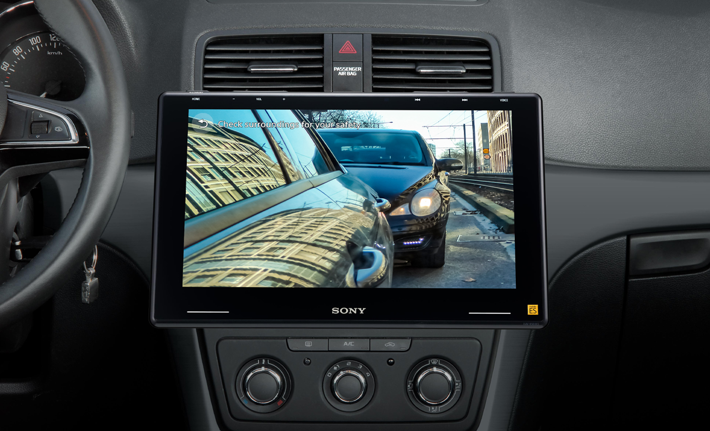 Interní pohled na palubní desku vozidla, zobrazující přehrávač XAV-9550ES s aktivní parkovací kamerou